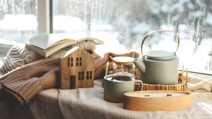 Cozy winter photo, stack of sweaters, book, tea and candle - obrazy, fototapety, plakaty