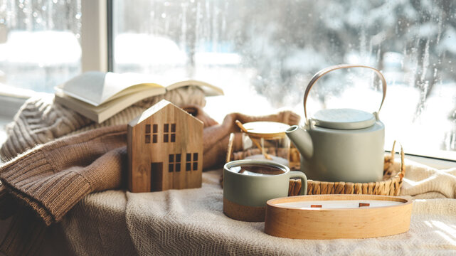 Cozy winter photo, stack of sweaters, book, tea and candle