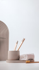 Bamboo toothbrushes in a stylish concrete glass on a white background