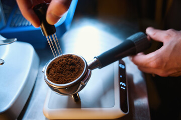 Barista leveling coffee in portafilter using specialized powder distributor