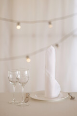 Elegant white dining setup with ambient lighting. Concept for romantic dinners, wedding receptions or upscale events. Copy space available.