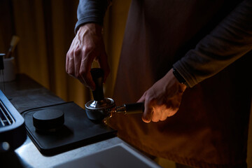 Barista holding portafilter and coffee tamper making hot beverage