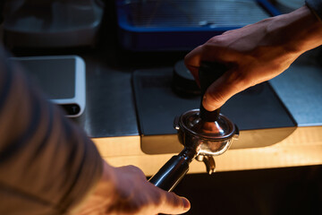 Barista holding portafilter and coffee tamper making an espresso coffee