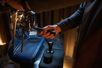 Barista hands holding portafilter and making fresh aromatic coffee