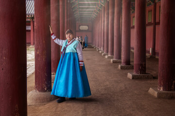 Female Asian tourist wearing traditional hanbok costume walking tours Gyeongbokguk Palace, South Korea.