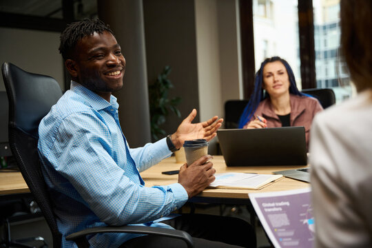 Positive colleagues laughing discussing applications development on the meeting