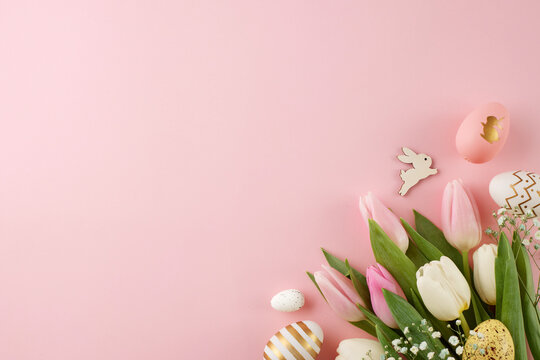 Easter festivity arrangements. Top view photo of colorful eggs, fresh tulips, easter bunnies on light pink background with promo space