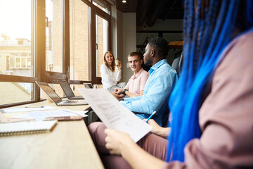 Friendly team communicating and drinking coffee sitting on working places