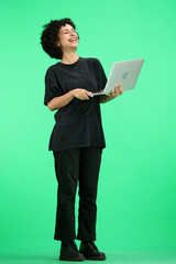 A woman, full-length, on a green background, with a laptop