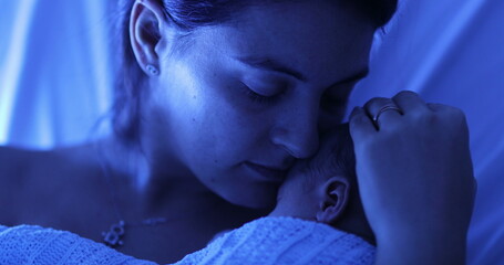 Mother holding newborn baby at hospital next to violet phototherapy lamp, real life affection and...
