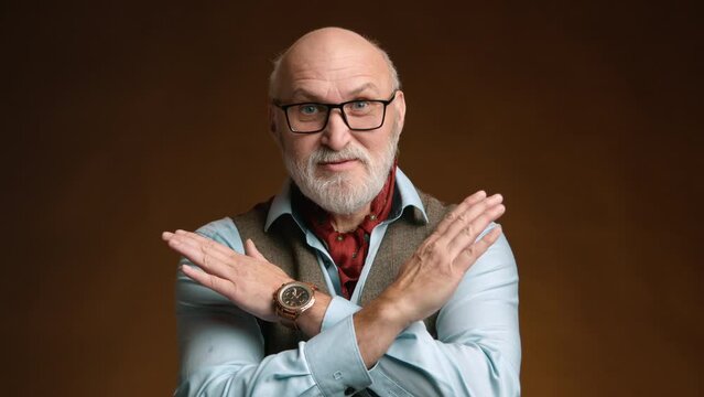 A distinguished older gentleman with a neatly trimmed beard shows a refusal gesture with his hands crossed. He wears a blue shirt, tweed vest, and a vividly patterned red scarf against. Camera 8K RAW