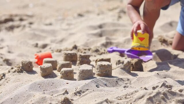 Close up sand cakes molding by child boy on the sandy beach near the sea. Vacation concept.