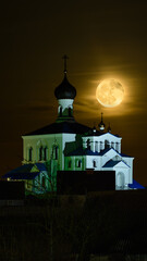 full moon in the dark night sky over the domes with crosses of the orthodox church with white walls