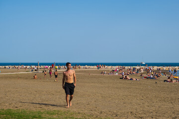 Young boy walking towards the camera on Malagueta beach in Malaga, Spain