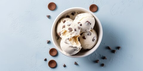 Glass bowl with scoops of ice cream, studded with chocolate pieces and interspersed with cookies, on a smooth blue background, Concept: summer sweet dessert. Banner with copy space