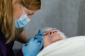 A specialist at the salon performs a series of small injections into the client's face.
