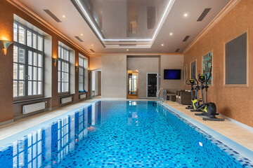 Magnificent private indoor swimming pool with mirrored ceiling and large windows.