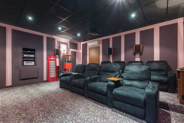 A home theater for private viewing, decorated in pink and lilac tones with luxurious gray armchairs.