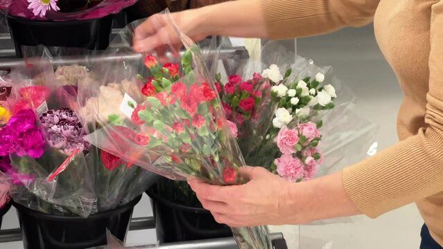 Flower bouquets in a shopping mall. Colorful bouquets of carnations and other flowers in the shopping center. A woman chooses a bouquet of small carnations for the celebration. Fresh flowers.