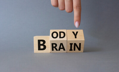 Body vs Brain symbol. Businessman hand points at turned wooden cubes with words Brain and Body. Beautiful grey background. Business and Body vs Brain concept. Copy space.