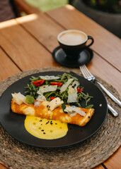 Omelette with cheese and salad on a plate, with a cup of coffee.