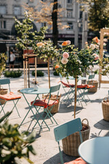 Tranquil outdoor cafe setting with blooming roses and blue metal furniture.