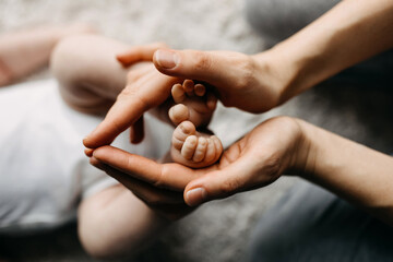 Mother hands holding a newborn child's feet, symbolizing love and care.