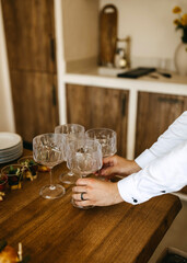 Person setting wine glasses on a wooden table.