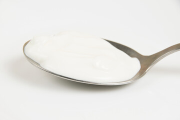 Sour cream or white sauce in a spoon on a white plate close-up