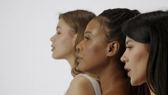 Portrait of multiethnic female models isolated on white background, face close shot. Group of three young multiracial girls line up at the camera. Multiethnic beauty concept.