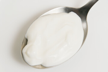 Sour cream or white sauce in a spoon on a white plate close-up