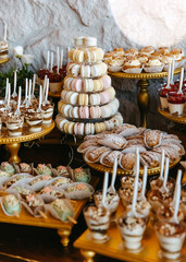A dessert table at an event with a variety of sweets on golden stands. Candy bar at a wedding.