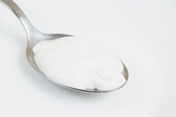 Sour cream or white sauce in a spoon on a white plate close-up