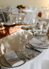 An elegantly set wedding reception table with plates, glasses and napkins.