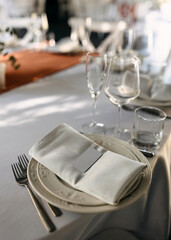 Wedding table setting with white plates, glasses, a folded napkin, and blank name card.