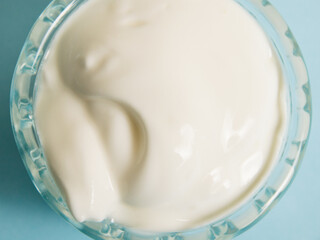 White sauce in a glass saucer on a blue background