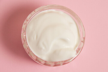 White sauce in a glass saucer on a pink background