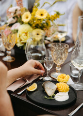 Elegant dining with fish plate, lemon, and mashed potato on black plate, yellow floral backdrop.