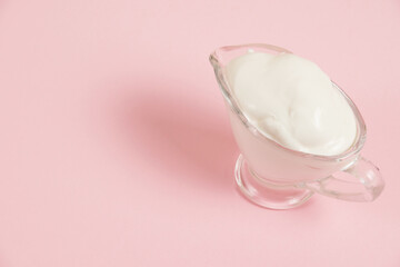 White sauce in a glass saucer on a pink background