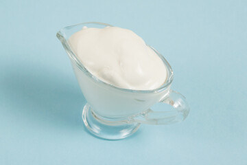 White sauce in a glass saucer on a blue background
