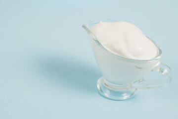 White sauce in a glass saucer on a blue background