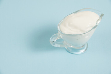 Obraz na płótnie Canvas White sauce in a glass saucer on a blue background