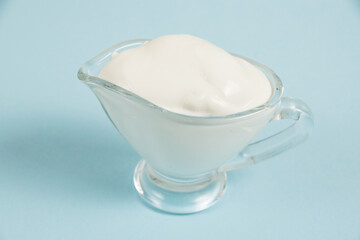 White sauce in a glass saucer on a blue background