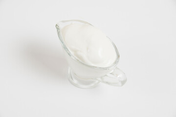 Obraz na płótnie Canvas Sour cream in a glass saucer on a white background