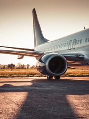 Backlit image of passenger airplane standing stationary on airport apron. Low evening sun creates a...