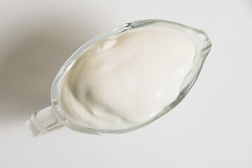 Sour cream in a glass saucer on a white background