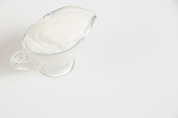 Sour cream in a glass saucer on a white background