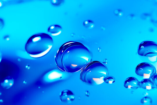 Close up of water droplets on blue surface with light blue background.