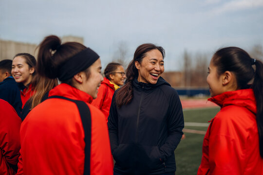 Female coach laughing with women's soccer team. Generative AI image