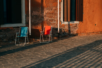 Blue and red armchairs on a street in Venice, Italy at sunset.